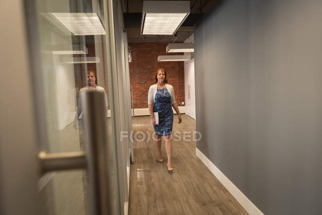 Вид на Кавказскую деловую женщину, идущую по служебному коридору — стоковое фото
