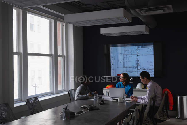 Vista lateral de diversos empresarios discutiendo entre sí en una reunión en la oficina - foto de stock
