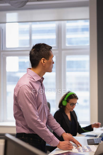 Vista lateral do pensativo empresário asiático em pé no escritório — Fotografia de Stock