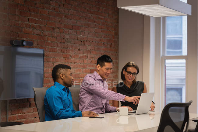 Боковой вид различных бизнесменов, обсуждающих за ноутбуком в конференц-зале в офисе — стоковое фото