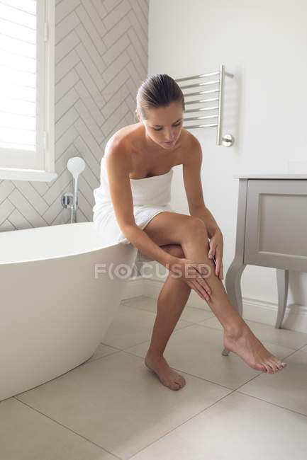 Mulher bonita aplicando loção em seu corpo no banheiro em casa — Fotografia de Stock