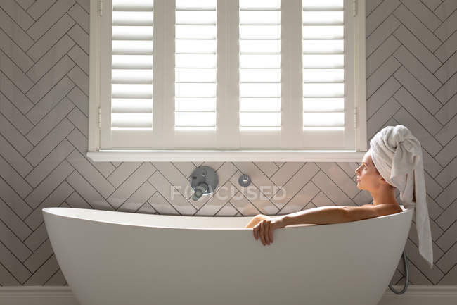 Mulher pensativa sentada na banheira no banheiro em casa — Fotografia de Stock