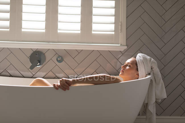 Mulher bonita relaxante na banheira no banheiro — Fotografia de Stock