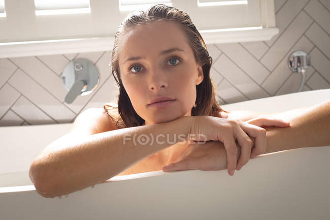 Nahaufnahme einer verträumten Frau, die sich im Badezimmer auf die Badewanne lehnt — Stockfoto