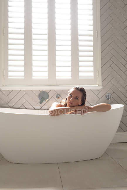 Schöne Frau lehnt an der Badewanne im Badezimmer zu Hause — Stockfoto