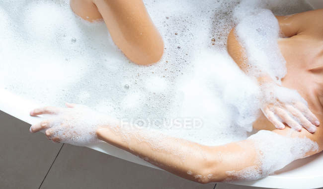 Media sezione di donna che fa il bagno nella vasca da bagno in bagno — Foto stock