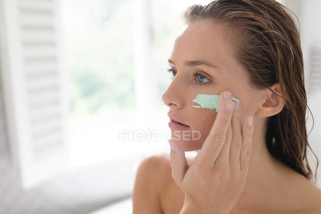 Nahaufnahme einer Frau, die nach einem Bad eine Gesichtsmaske aufträgt — Stockfoto