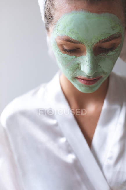 Frontansicht einer Frau mit Gesichtsmaske, die zu Hause nach unten schaut — Stockfoto