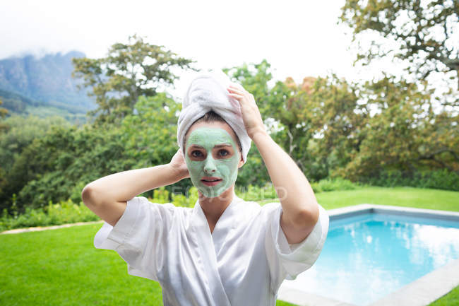 Portrait of woman in face mask looking at camera near poolside — Stock Photo