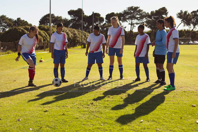 Передній план різноманітних футболісток, які практикують футбол на спортивному полі в сонячний день — стокове фото