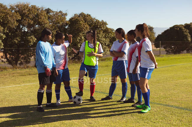 Front view of diverse female soccer players interacting with each other at sports field on a sunny day — Stock Photo