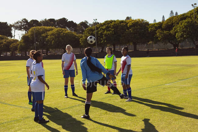 Vue arrière de diverses joueuses de soccer jouant au soccer sur un terrain de sport par une journée ensoleillée — Photo de stock