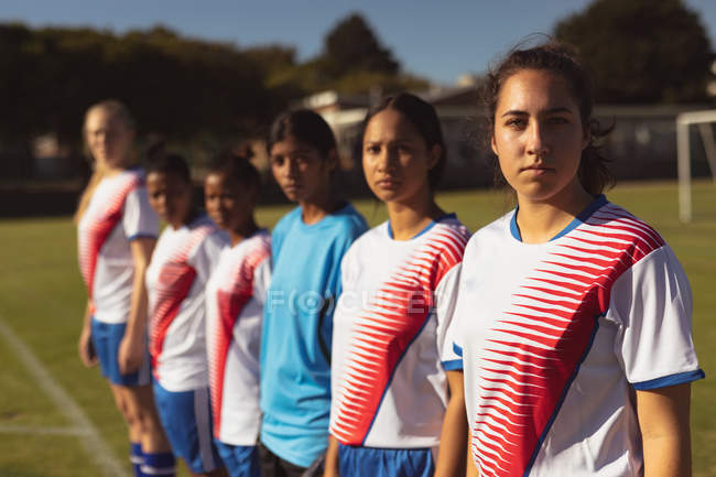 Side view of diverse female soccer players looking at camera at sports field on a sunny day — Stock Photo