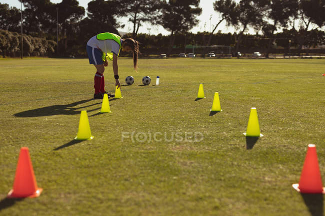 Vista laterale del calciatore caucasico che organizza coni sul campo per allenarsi in una giornata di sole — Foto stock