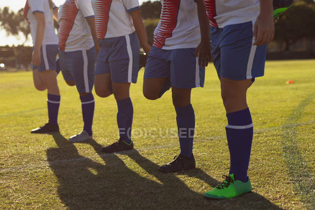 Mid section of female soccer players doing warm-up exercise on the field on a sunny day — Stock Photo
