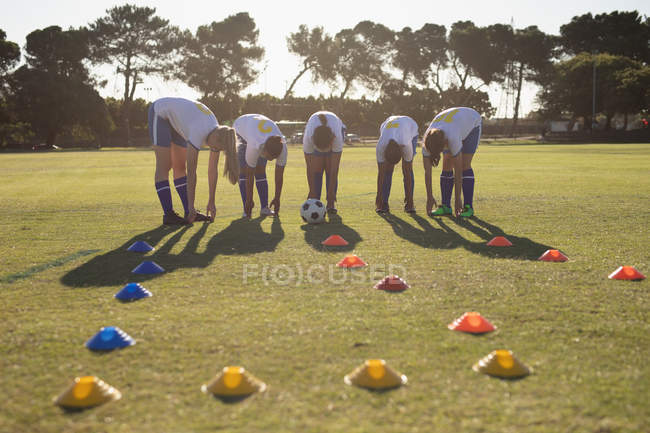Вид спереду на різноманітних футболісток, які роблять вправи для розминки на полі в сонячний день — стокове фото