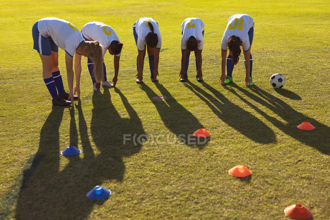 Front view of diverse female soccer players doing warm-up exercise on the field on a sunny day — Stock Photo