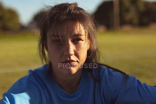 Retrato de exausto jogador de futebol asiático sentado no campo depois de um treino em um dia ensolarado — Fotografia de Stock