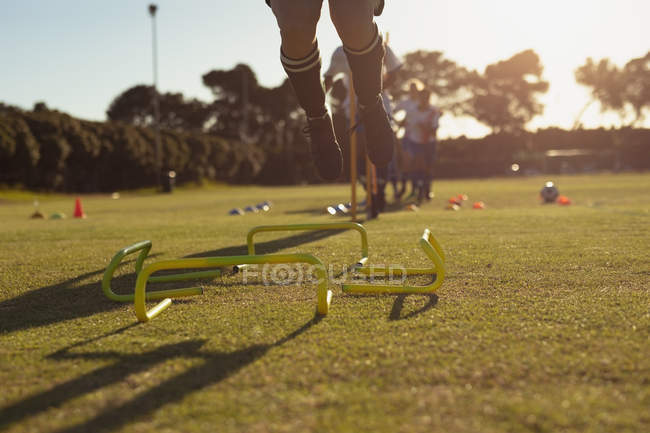 Sezione centrale del giocatore di calcio femminile saltare oltre ostacolo durante l'allenamento al campo sportivo — Foto stock
