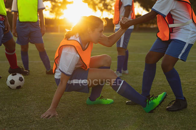 Vista lateral de diversas jogadoras de futebol fazendo exercícios de aquecimento no campo esportivo durante o torneio — Fotografia de Stock