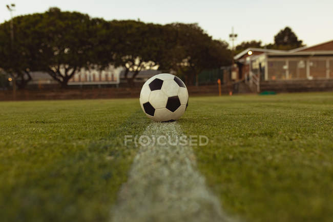 Soccer ball on white line in sports field — Stock Photo