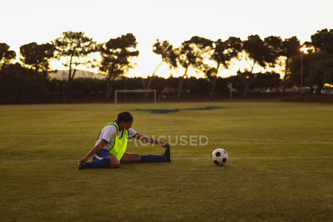 Side view of African-american female soccer player doing warm-up exercises at sports field during tournament — Stock Photo
