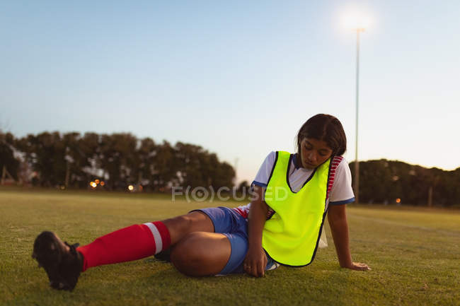Вид з афро-американського жіночого футболіста відпочиваючи на траві на спортивному полі — стокове фото
