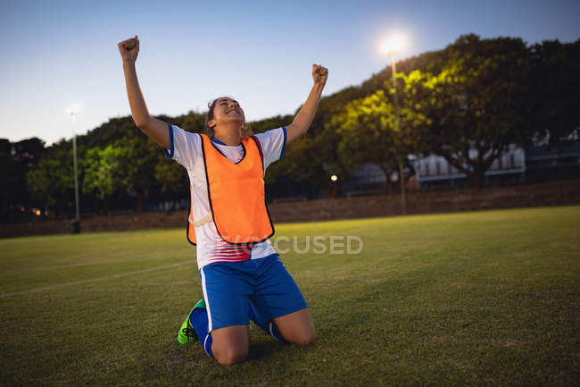 Front view of carefree African-american female soccer player cheering after victory at sports field — Stock Photo