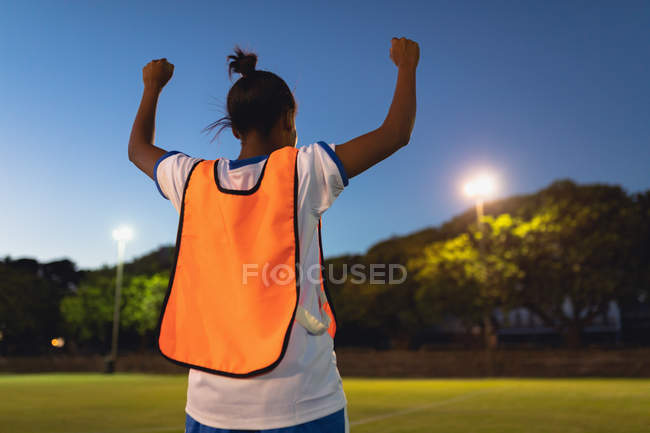 Rear view of African-American female soccer player cheering after victory at sports field — Stock Photo