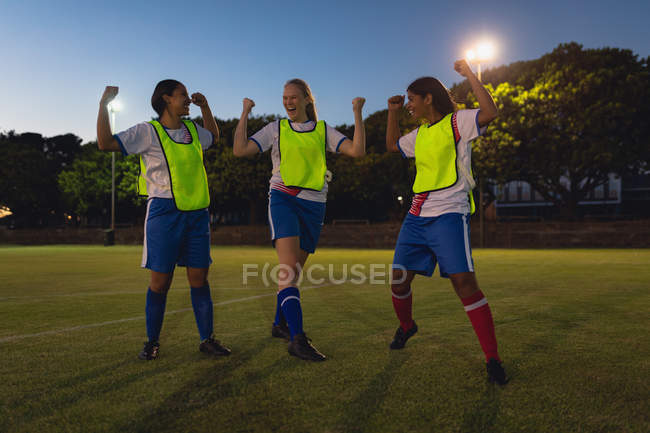 Front view of diverse female soccer players cheering at sports field after victory — Stock Photo