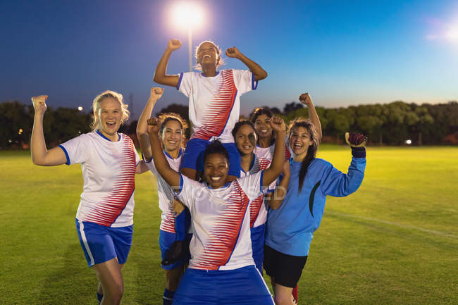 Vue de face de diverses équipes féminines de football applaudissant leur victoire sur le terrain de sport — Photo de stock