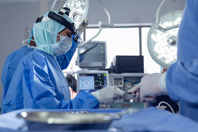 З боковим видом на різні хірурги виконання операції в театрі операцій в лікарні. — стокове фото