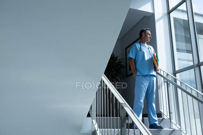 Baixo ângulo vista de pensativo maduro caucasiano médico masculino em pé nas escadas do hospital — Fotografia de Stock