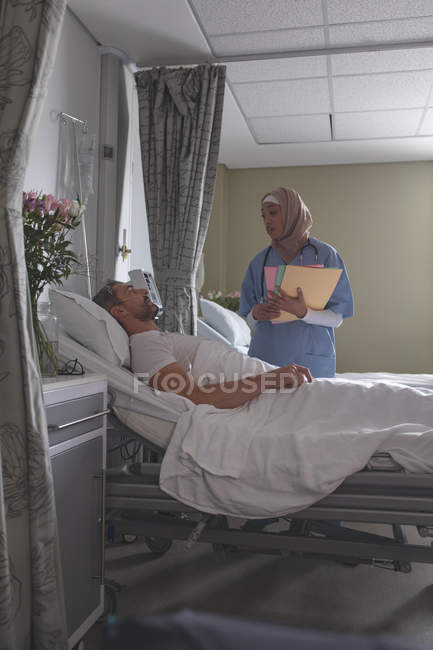 Vista frontale del medico di razza mista che interagisce con il paziente maschio caucasico nel reparto ospedaliero — Foto stock