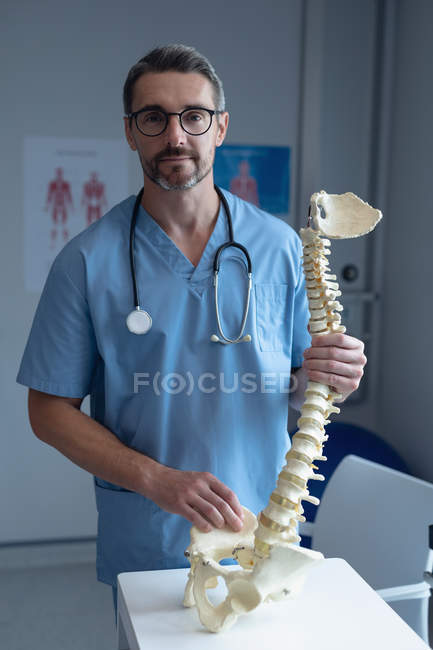 Портрет Кавказького чоловічого ортопедичного хірурга з стетоскоп навколо шиї Холдинг хребта моделі в лікарні — стокове фото