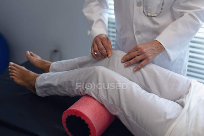 Sezione centrale del medico femminile che utilizza rullo di schiuma sulla gamba della paziente in ospedale — Foto stock