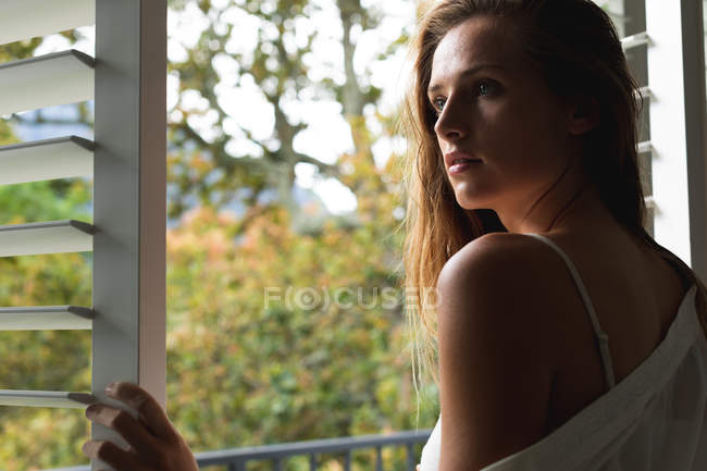 Vista laterale di una donna caucasica premurosa che sta vicino alla porta di casa — Foto stock