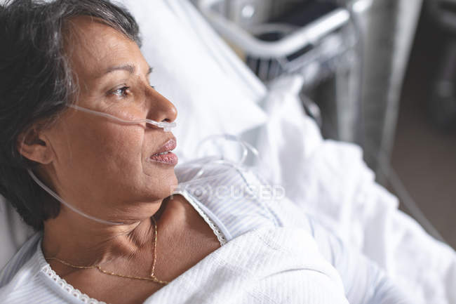 Close up of thoughtful mixed race female patient relaxing in bed in the ward at hospital — Stock Photo