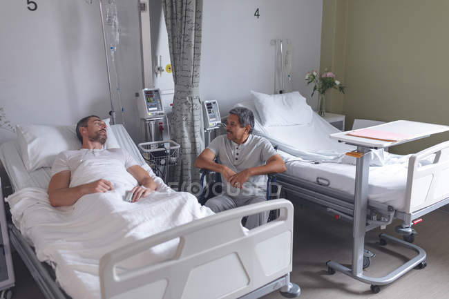 Vista frontale di diversi pazienti maschi che interagiscono tra loro nel reparto ospedaliero . — Foto stock