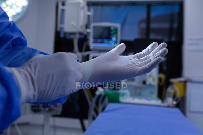 Mid section of male surgeon wearing medical gloves in operation theater at hospital — Stock Photo