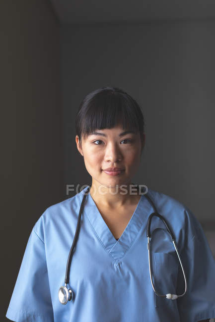 Retrato de feliz asiático médico feminino de pé com estetoscópio em torno de seu pescoço no hospital — Fotografia de Stock