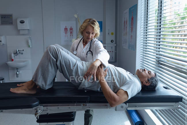 Vorderansicht einer kaukasischen Ärztin, die einen älteren Mischlingspatienten wieder im Krankenhaus untersucht — Stockfoto