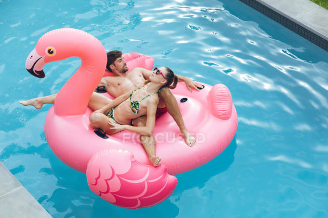 High view of Caucasian couple sleeping together on a inflatable tube in swimming pool in the backyard — Stock Photo