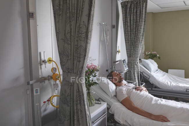 Side view of Caucasian male patient sleeping with his hand on chest in bed in the ward at hospital — Stock Photo