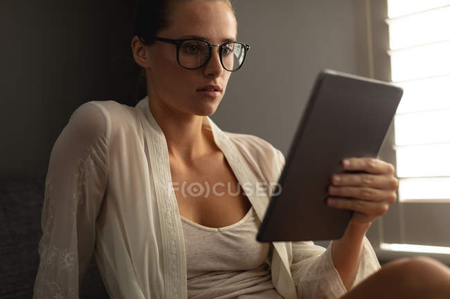 Front view of Caucasian woman using digital tablet on a sofa in living room at home — Stock Photo