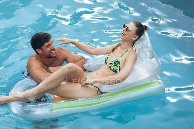 Vista alta de pareja caucásica feliz divirtiéndose juntos en la piscina - foto de stock
