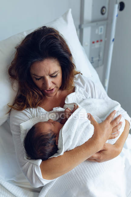 Высокий угол обзора красивой матери, держащей своего новорожденного ребенка после родов в палате больницы — стоковое фото