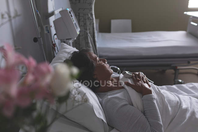 High angle view of thoughtful mixed-race female patient relaxing in bed in the ward at hospital — Stock Photo