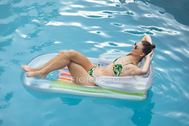 Vista alta da bela mulher caucasiana em biquíni relaxante em um tubo inflável na piscina — Fotografia de Stock