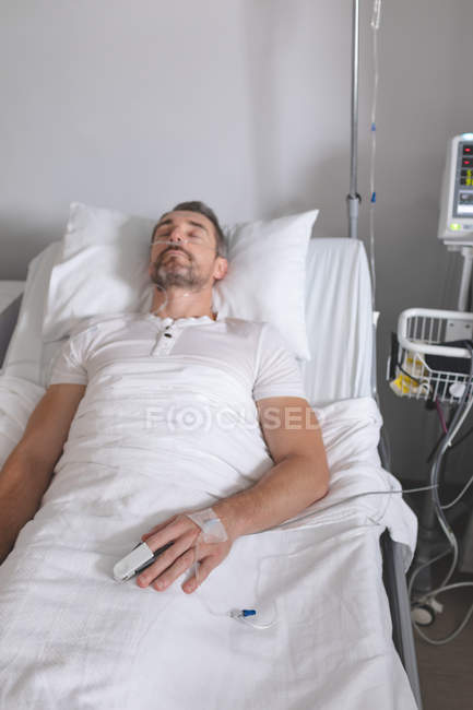 Vista frontale del paziente maschio caucasico che dorme nel letto nel reparto dell'ospedale — Foto stock